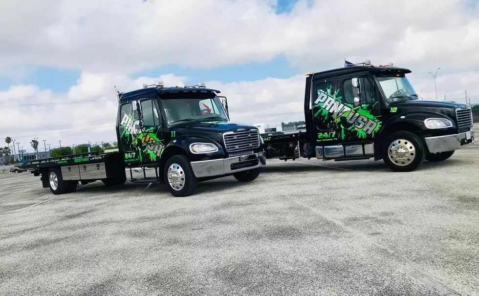 Two black tow trucks in a parking area